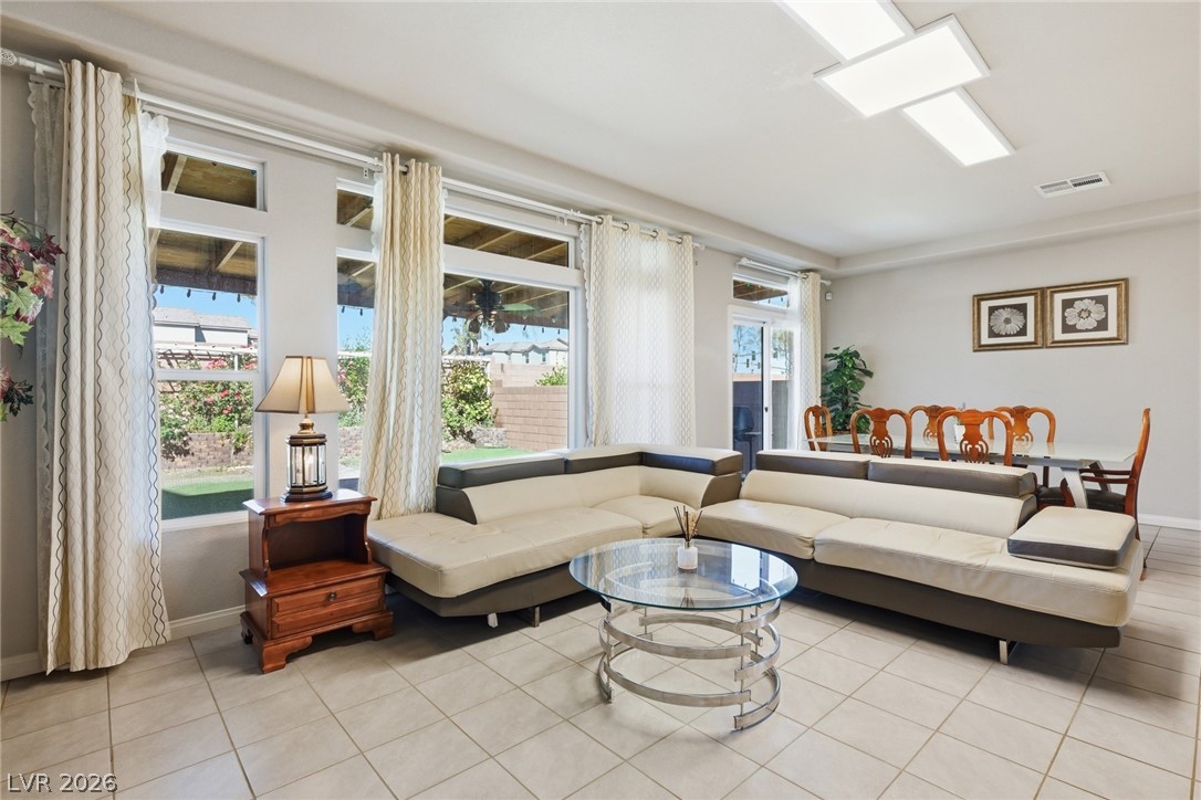 Living room with a cream sectional, glass coffee table, and large windows overlooking the backyard.
