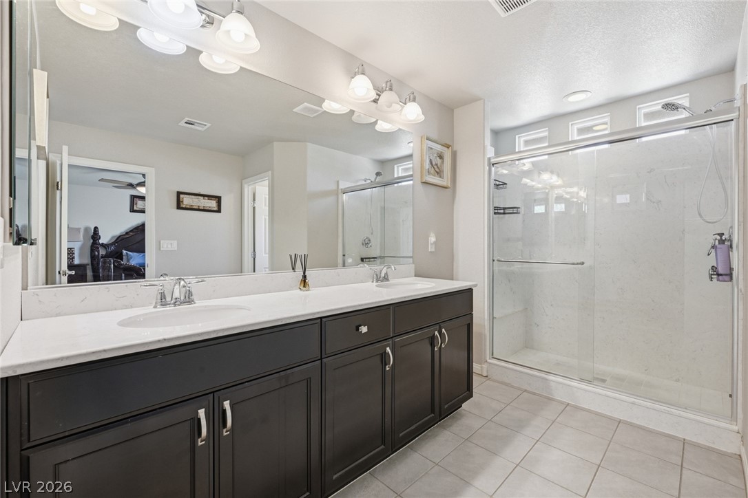 Bathroom with a dark double vanity, broad mirror, and glass-enclosed walk-in shower.