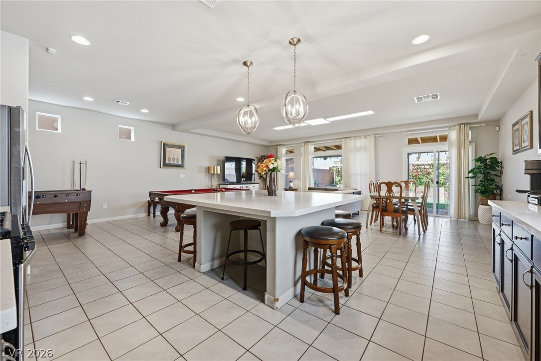Spacious kitchen with a large white island, bar stools, and an adjoining dining area.