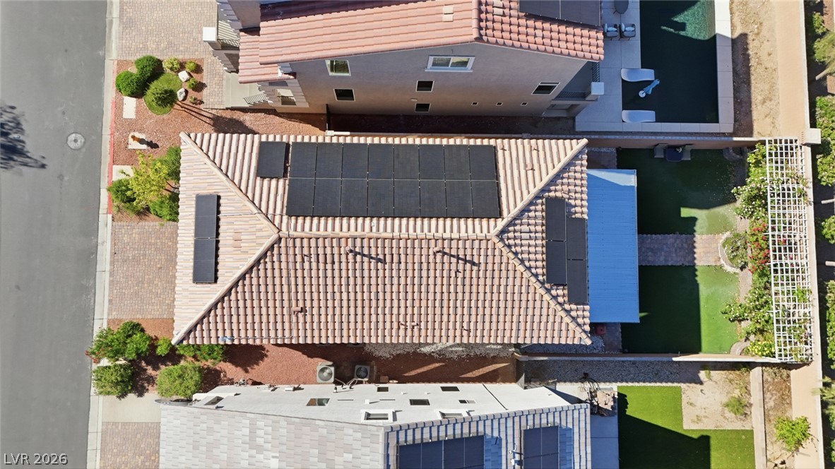 Aerial view of a tile-roofed home with solar panels and landscaped yards.
