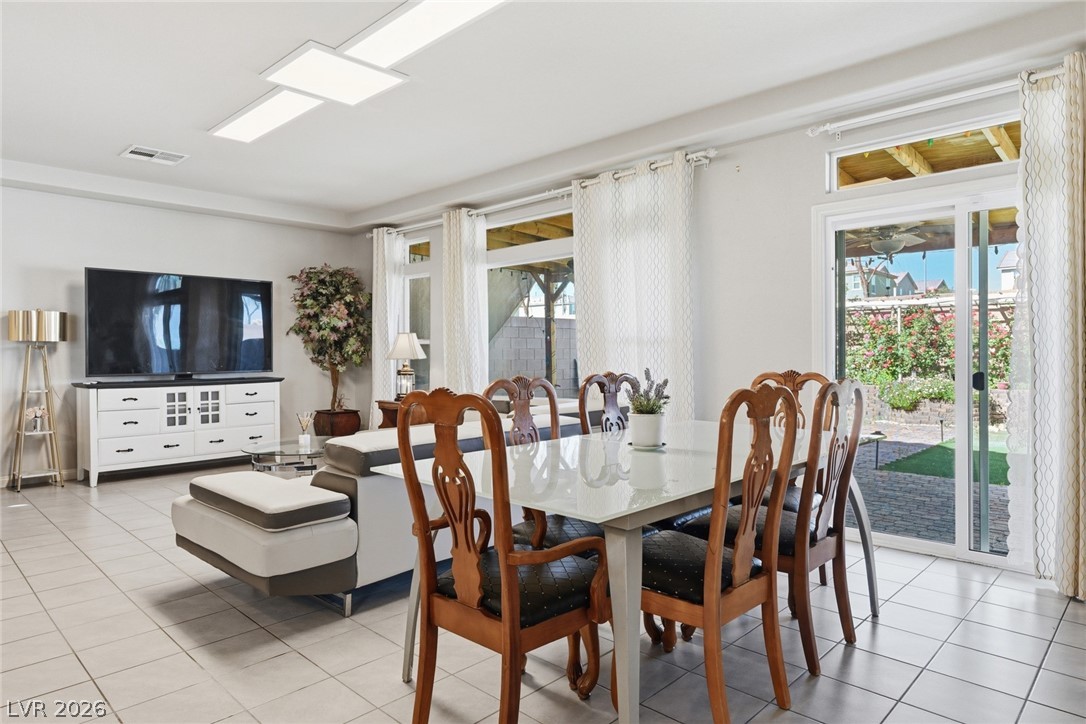 Dining area with a glass-top table and carved wooden chairs beside sliding doors to the backyard.