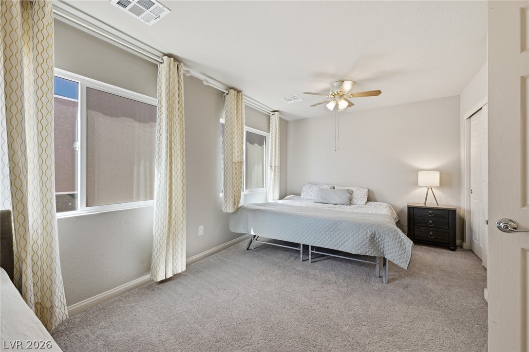 Furnished bedroom with a large bed, wide windows, and patterned curtains.