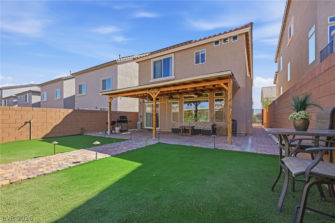 Backyard with artificial turf, paver paths, patio seating and a covered wooden pergola.
