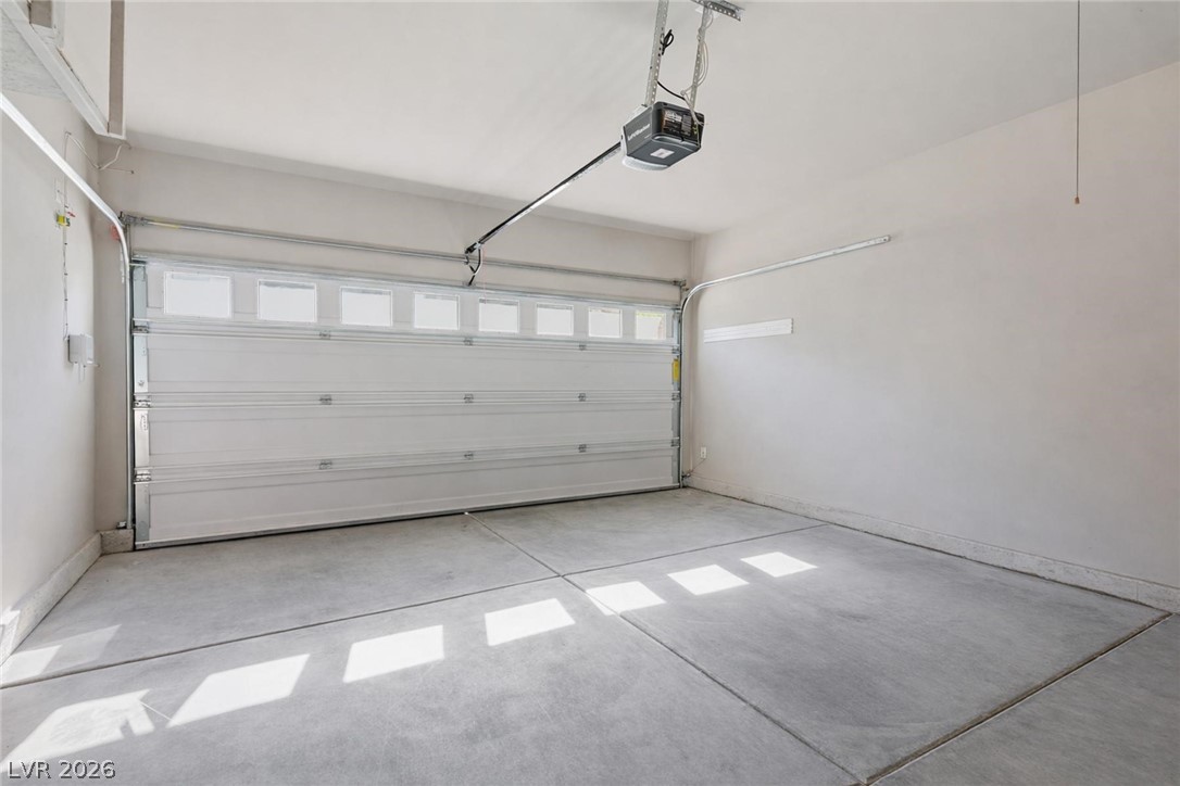 Empty garage with a closed white sectional door and sunlight across the concrete floor.