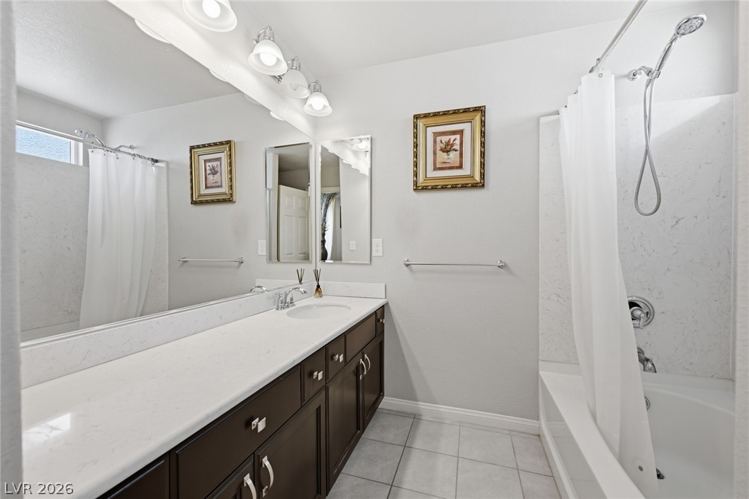 Bathroom with a long white vanity, dark cabinets, and a tub-shower behind a curtain.