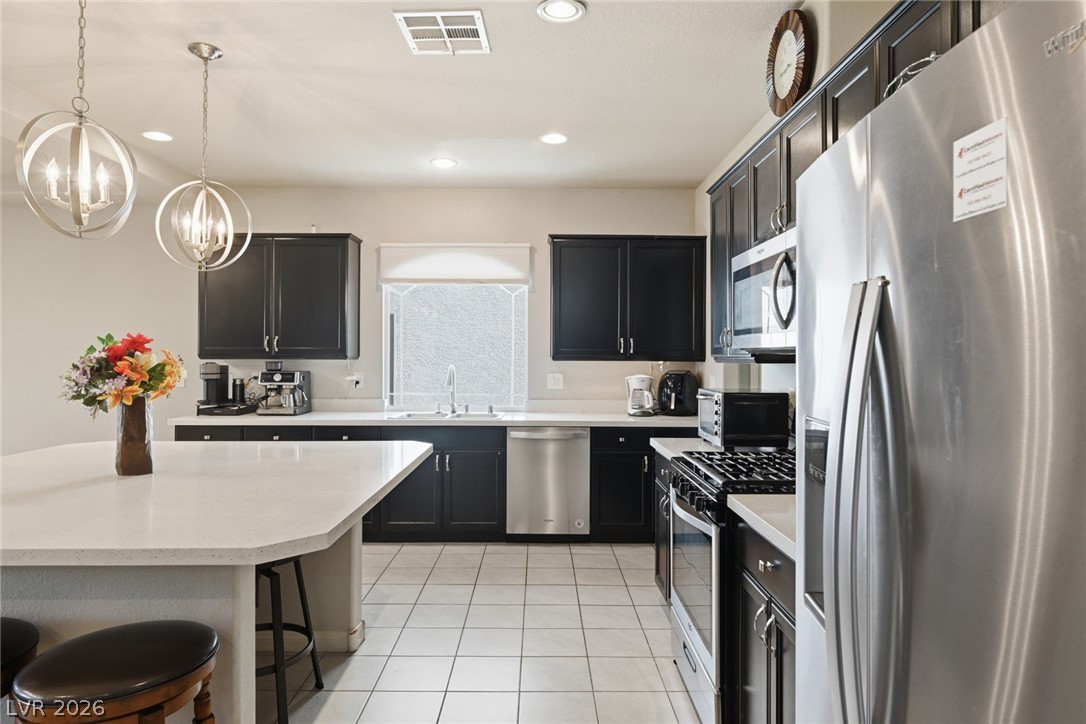 Kitchen with dark cabinets, stainless steel appliances, and a broad white island.