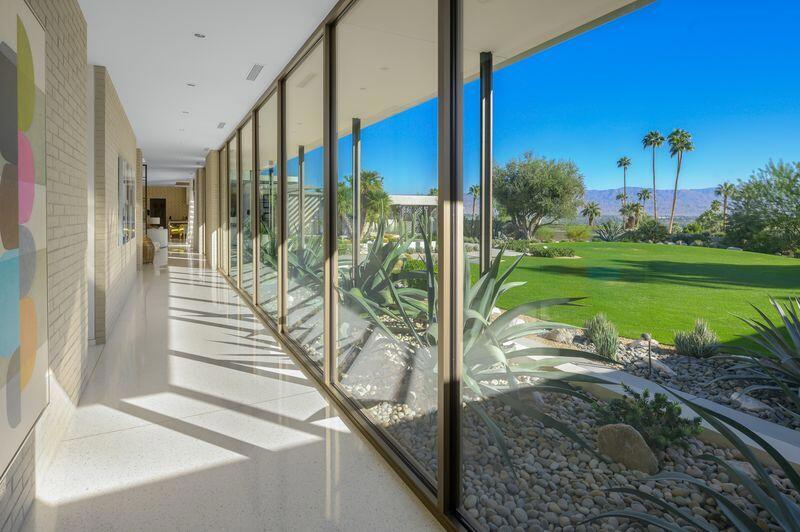 Bright hallway with floor-to-ceiling windows overlooking a golf course and distant mountains.