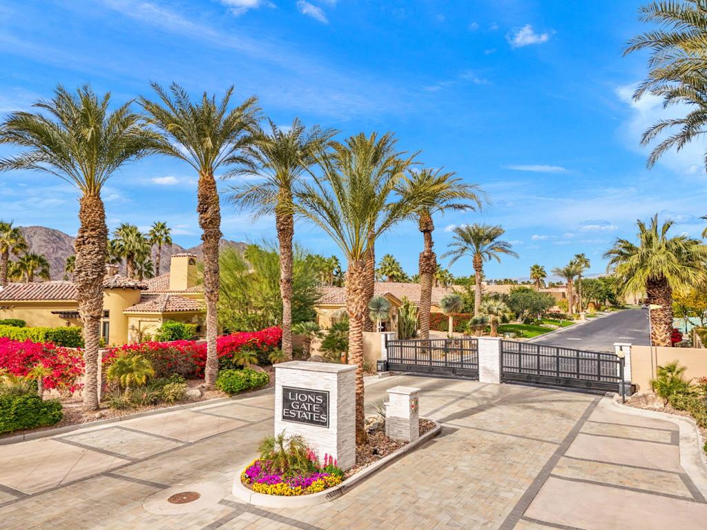 Lions Gate Estates entrance with palm trees, landscaped grounds, and a gated driveway.