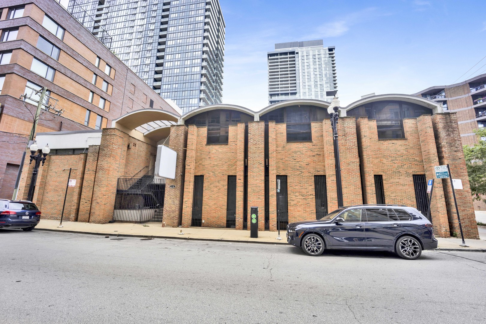 Red brick building with a curved roof, framed by modern high-rise buildings.