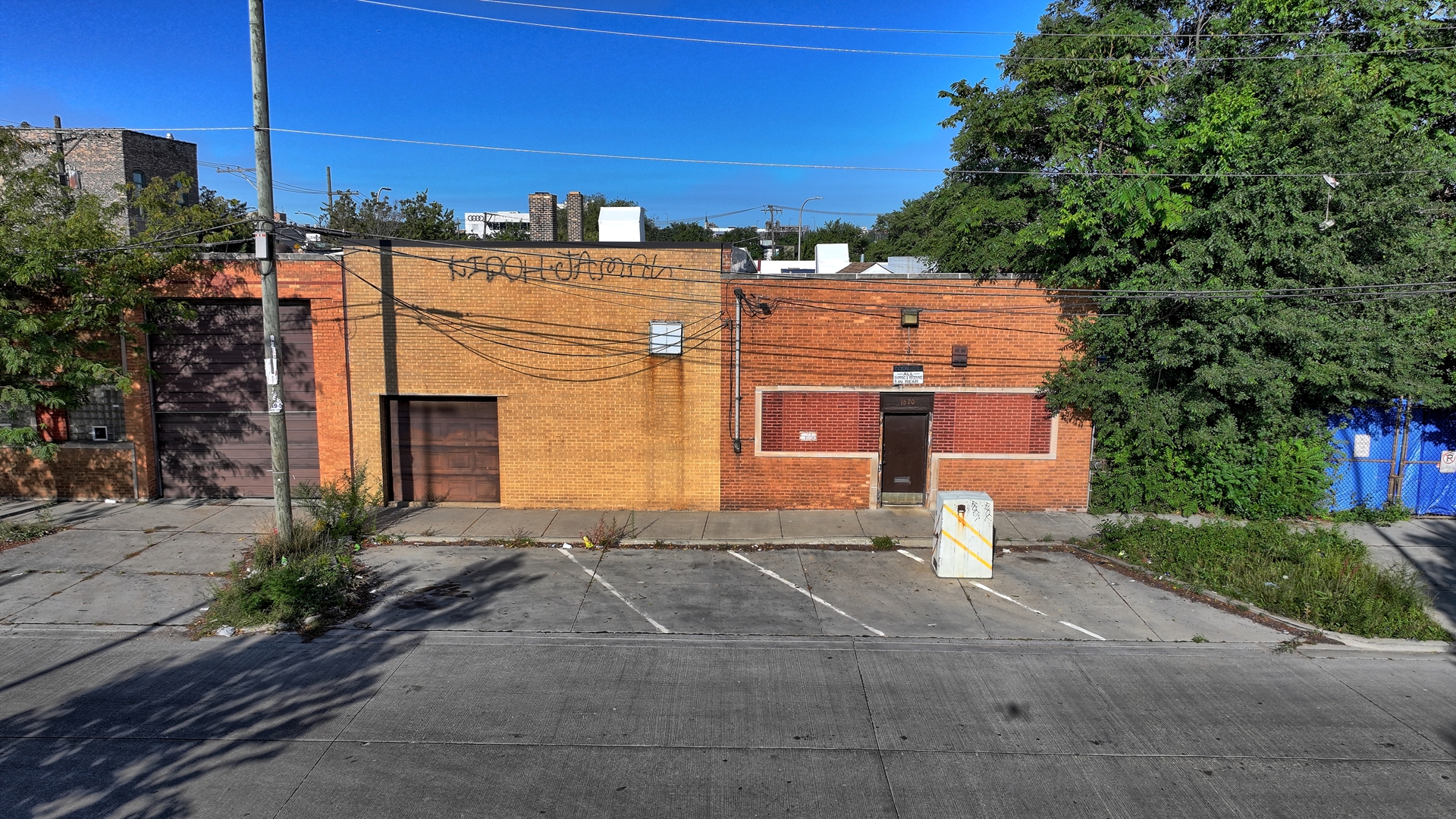 Low-rise brick commercial building with two garage doors and marked parking spaces along the street.