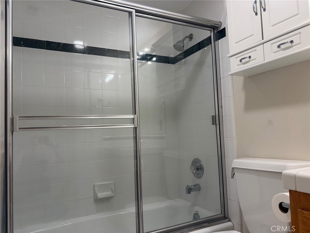 Bathroom with a white tiled tub and sliding glass shower doors.