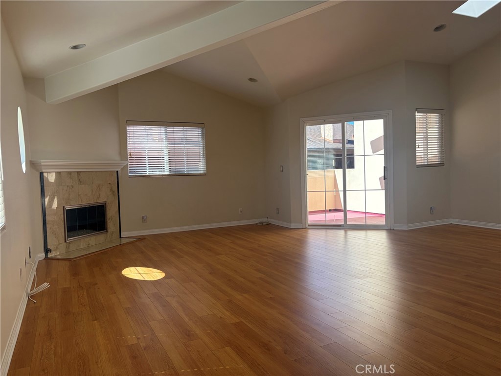 Vacant living room with wood floors, a stone fireplace, and sliding glass doors to a patio.