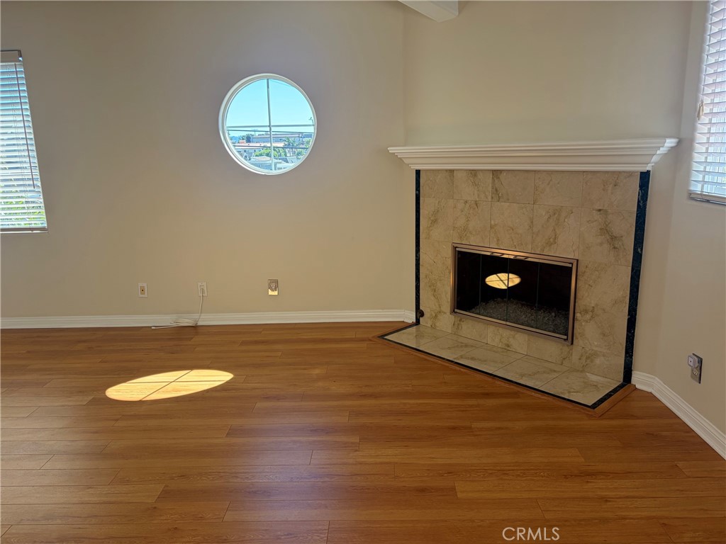 Unfurnished living room with a marble fireplace, wood floors, and a round window.
