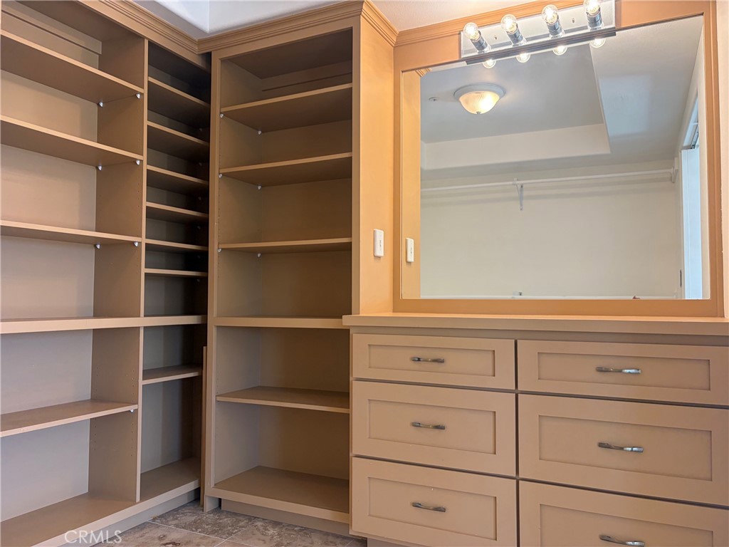 Walk-in closet with built-in shelving, drawers, and a large mirror.