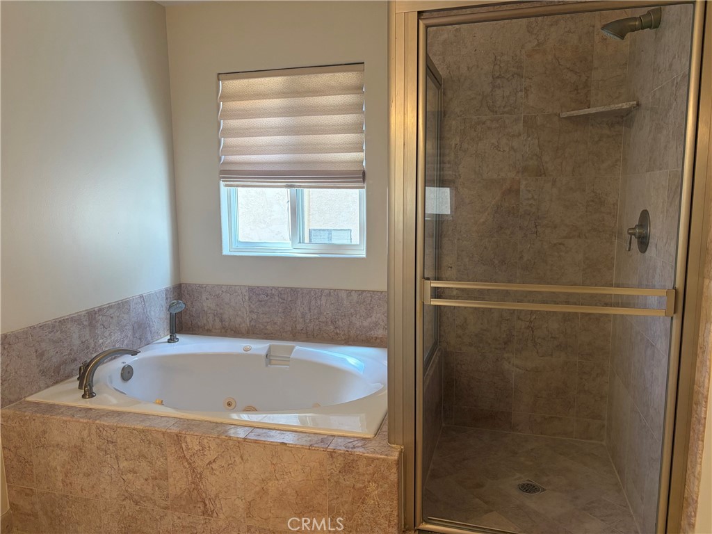 Bathroom with a built-in jetted tub beside a glass-enclosed stone-tile shower.