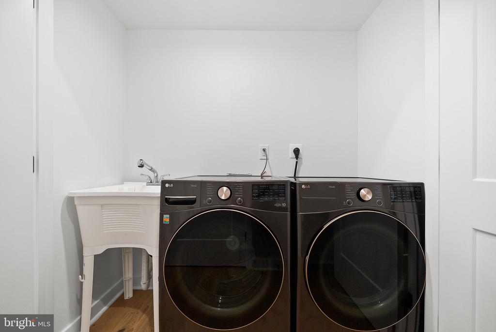 Laundry room with black LG front-loading washer and dryer beside a white utility sink.
