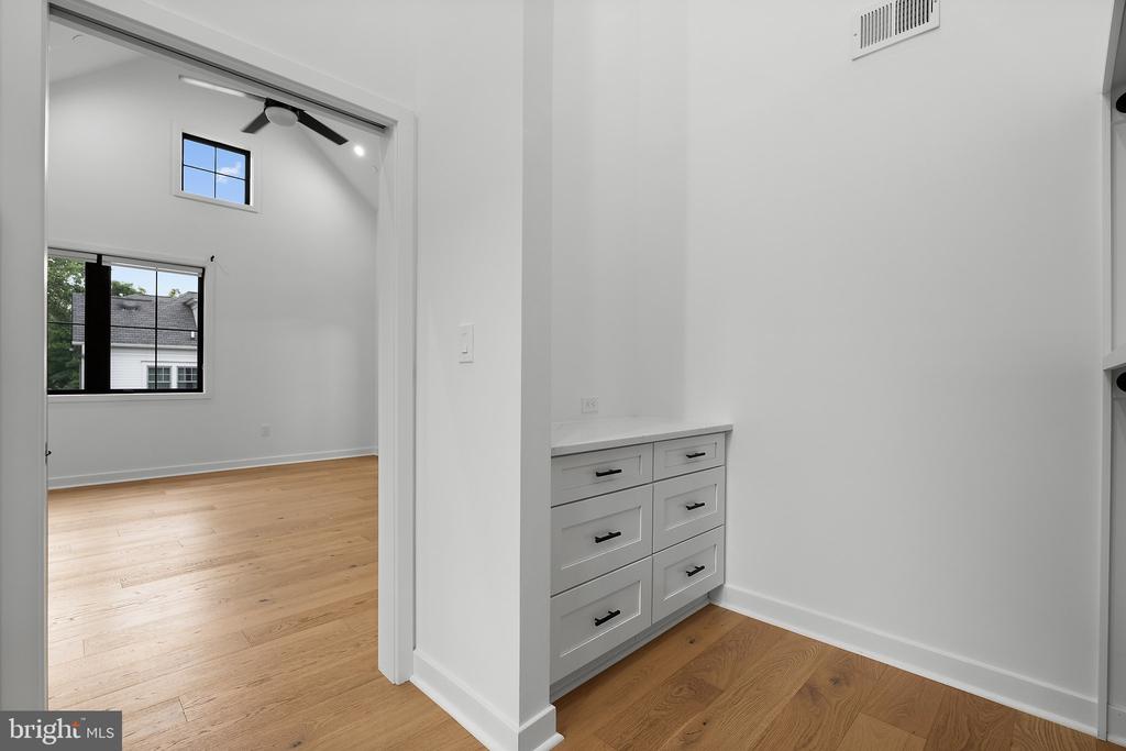 Bedroom with hardwood floors and ceiling fan beside a built-in drawer cabinet.