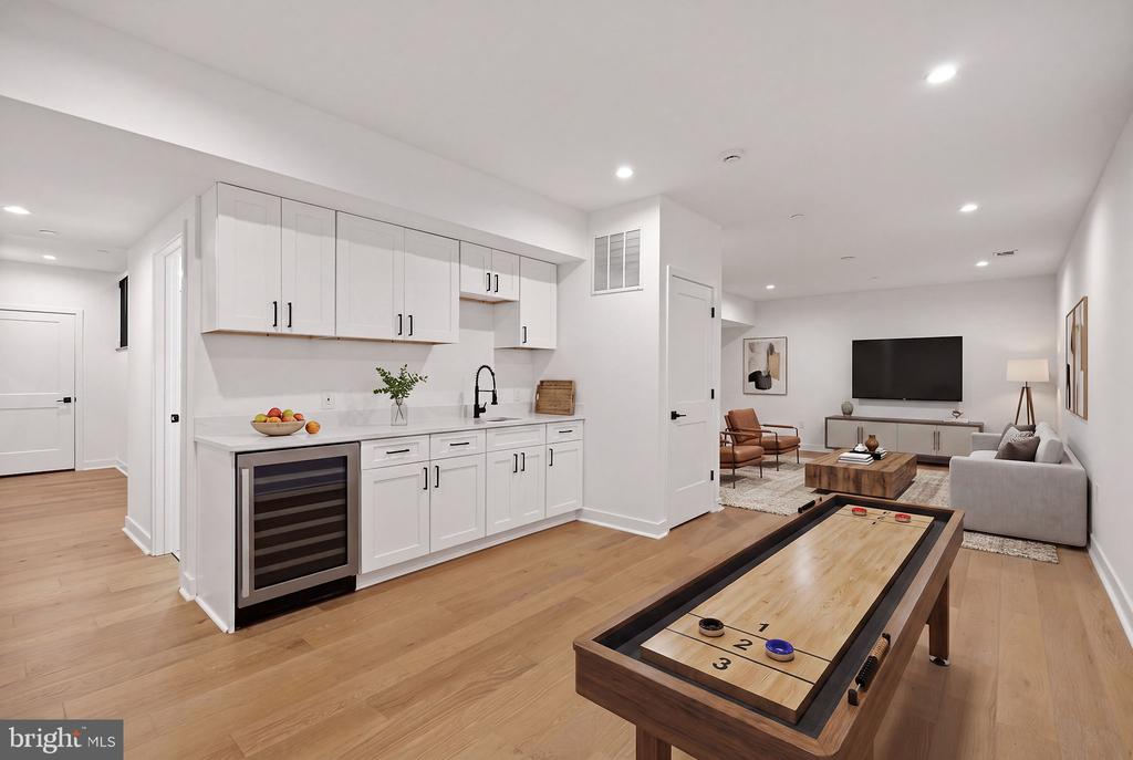 Furnished recreation room with a white kitchenette, shuffleboard table, and TV sitting area.