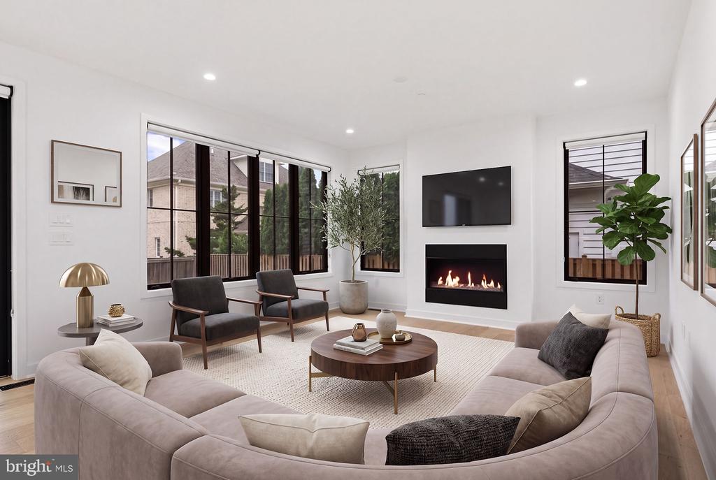 Staged living room with a curved sectional, large windows, and a linear fireplace.