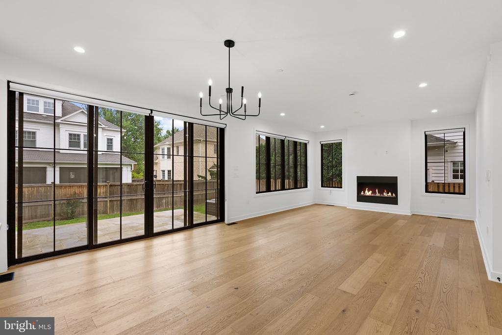Vacant living room with hardwood floors, a fireplace, and large windows opening to a patio.