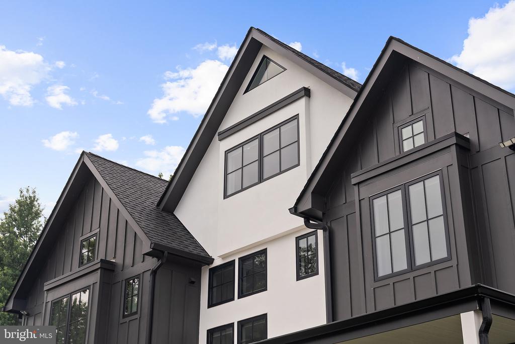 Modern house with dark siding, a white central gable, and steep rooflines.
