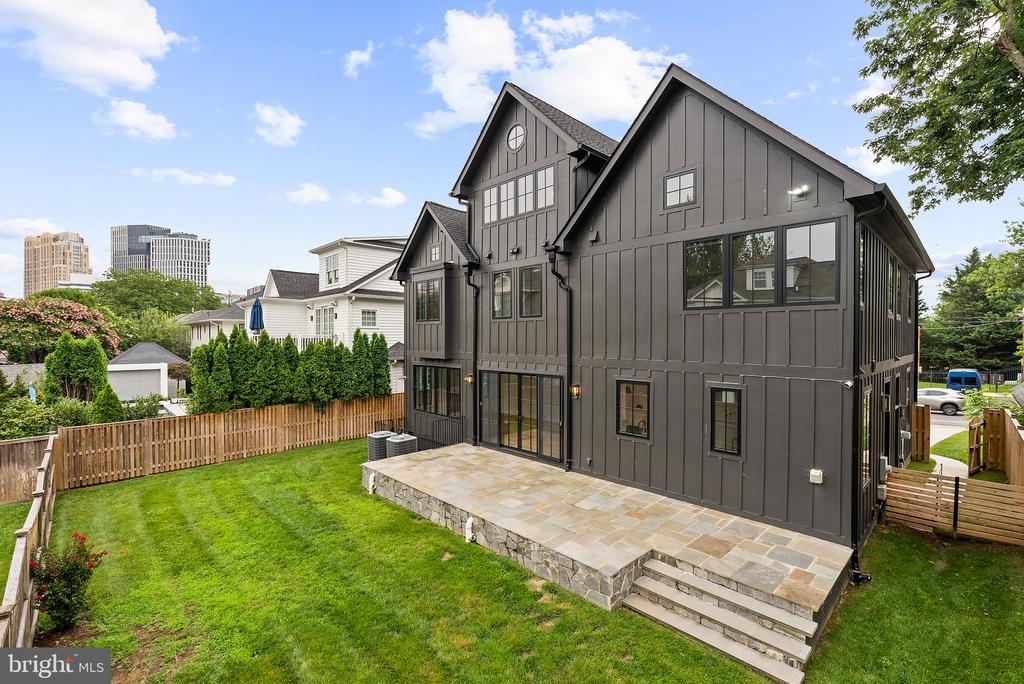 Charcoal-gray Bethesda home with a stone patio, fenced lawn, and multiple gabled rooflines.