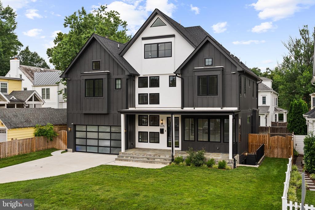 Modern charcoal-and-white house with a covered porch, two-car garage, and broad front lawn.