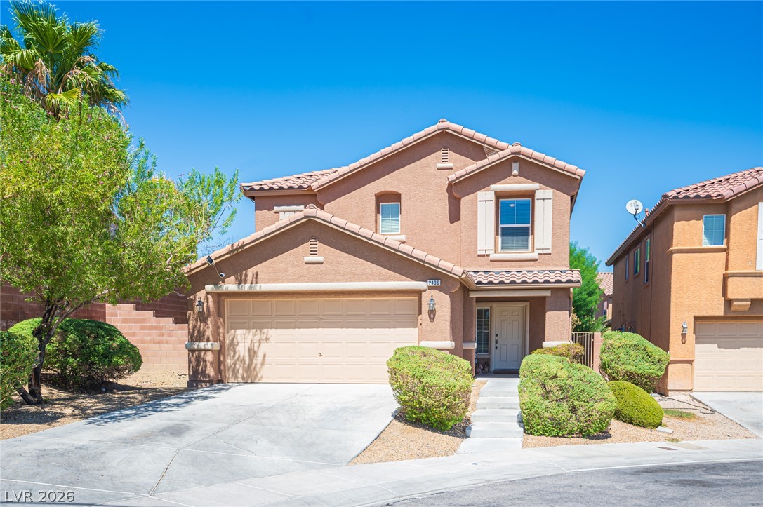 Two-story stucco house with a double garage, tiled roof, and desert landscaping.