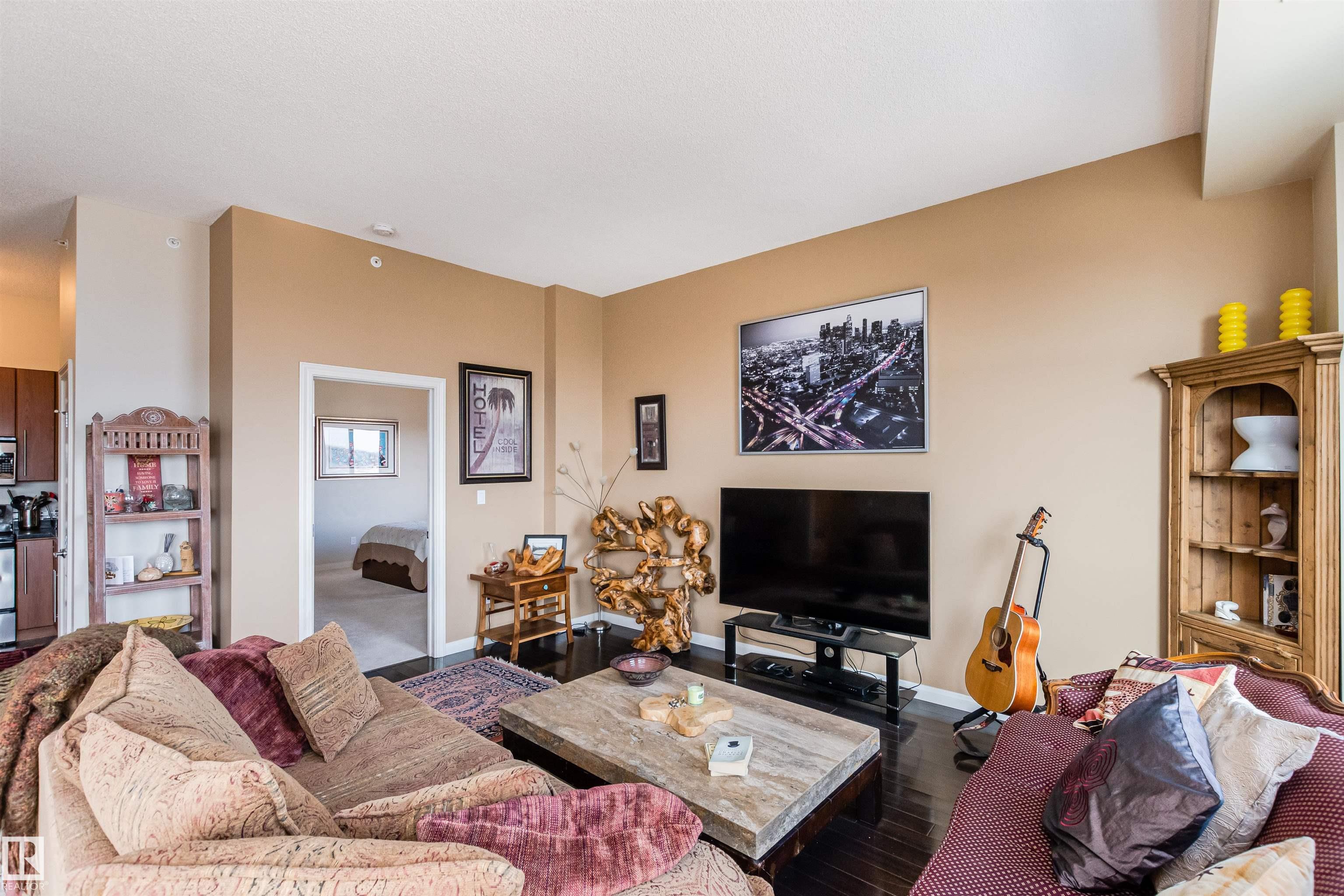 Furnished condo living room with two patterned sofas, a stone coffee table, and a guitar.