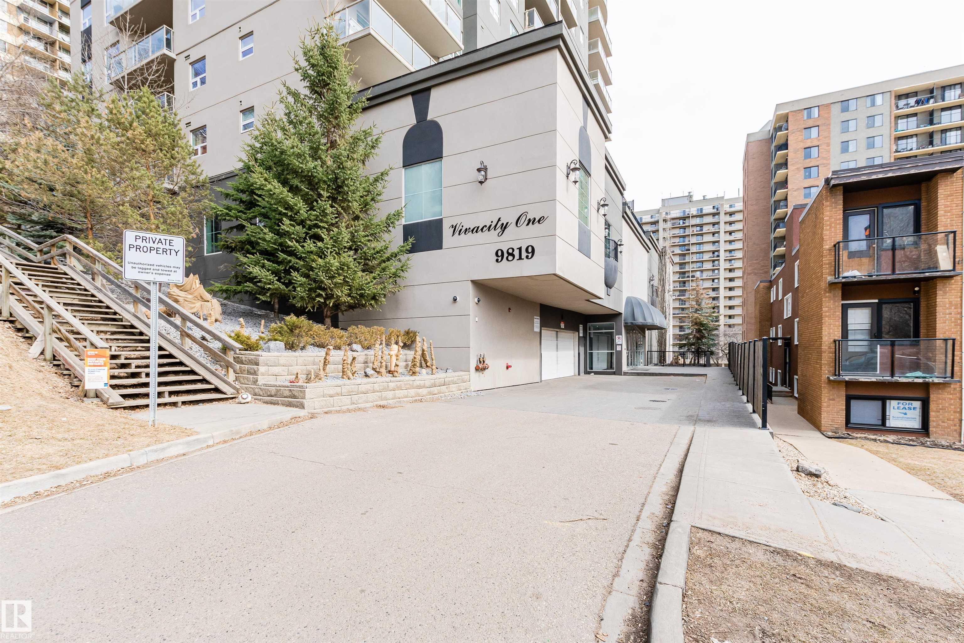 Vivacity One condominium entrance beside landscaped stairs and a driveway.