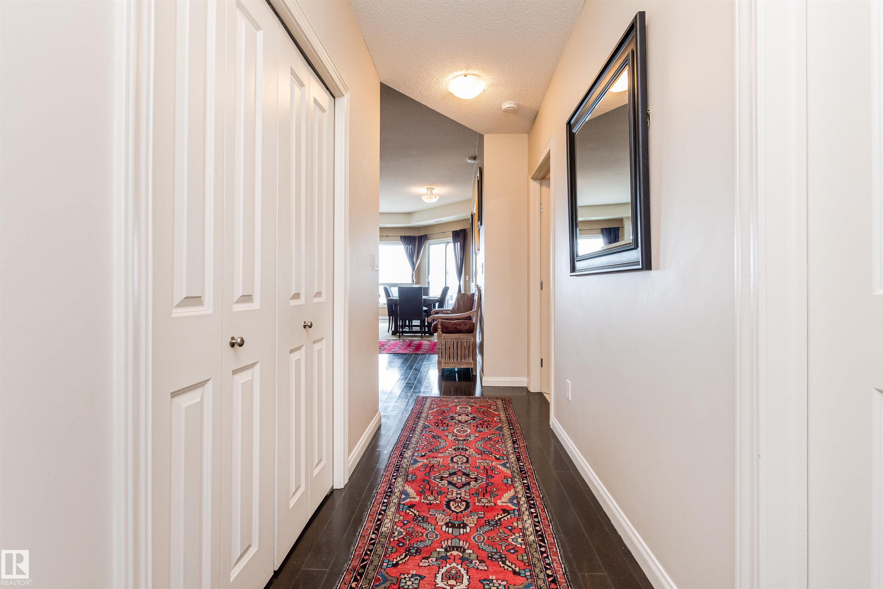 Condo hallway with a red patterned runner, white closet doors, and a mirror.