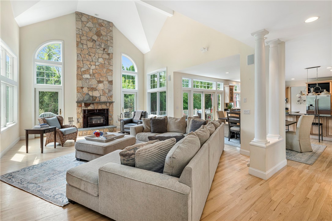 Living room with a stone fireplace, tall arched windows, vaulted ceiling, and large sectional sofa.