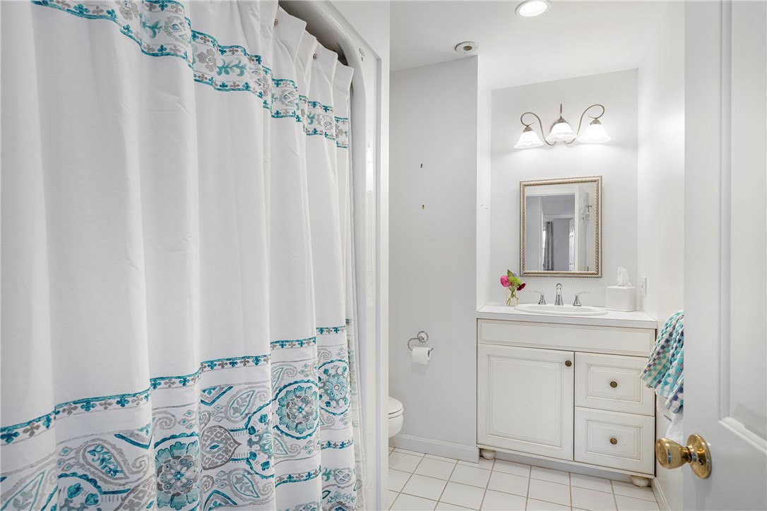 Bathroom with white vanity and a teal-patterned shower curtain.