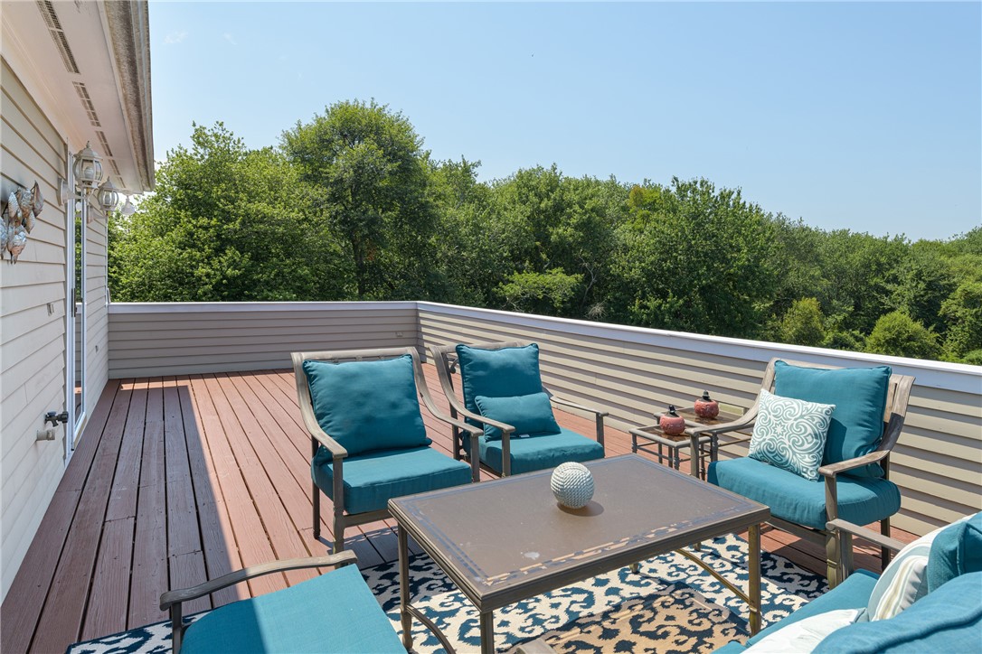 Furnished deck with teal seating, a coffee table, and a wooded view.