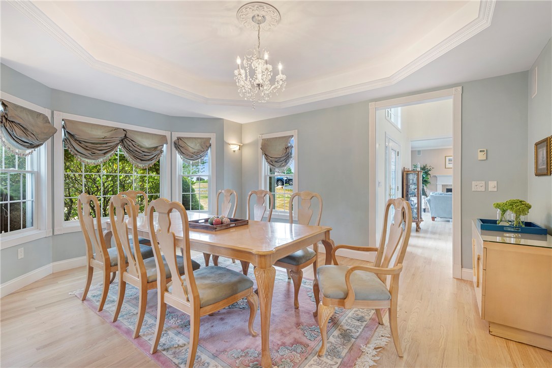 Dining room with a wood table, gathered window shades, patterned rug, and chandelier.