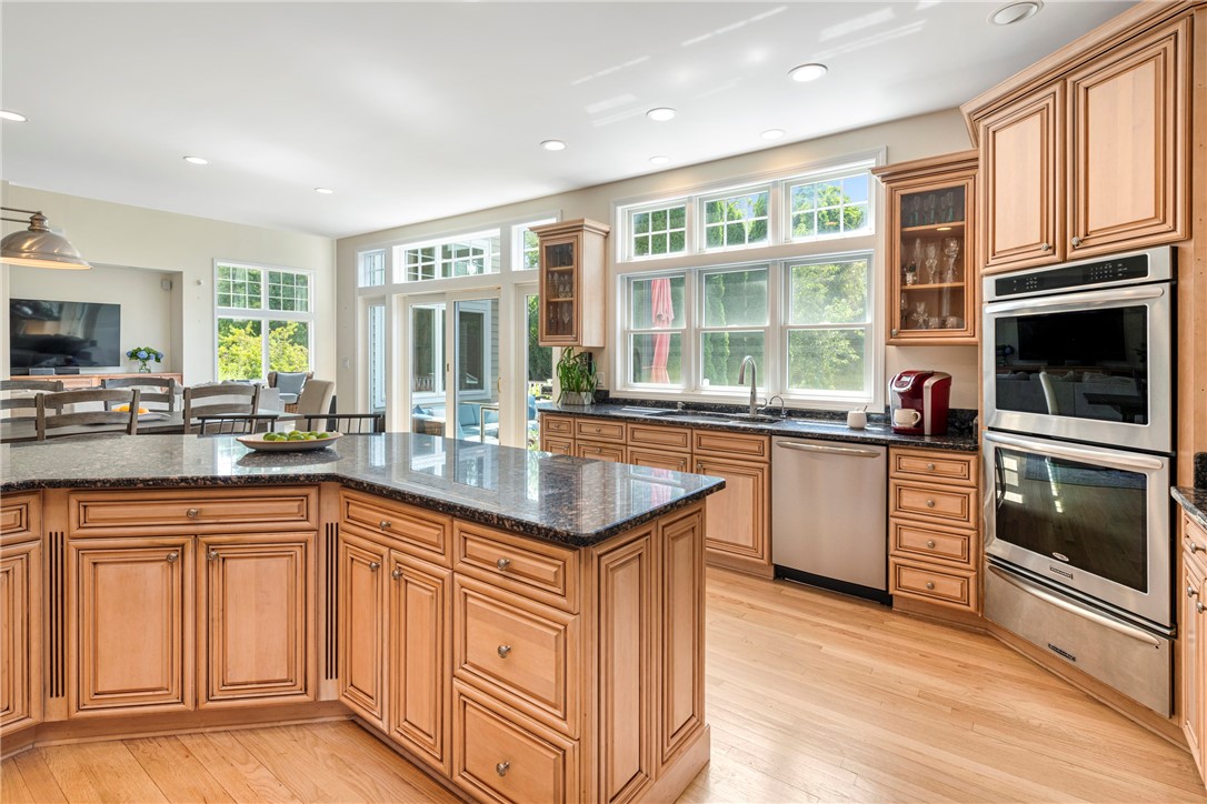 Bright kitchen with a large stone-topped island, warm wood cabinetry, and abundant windows.