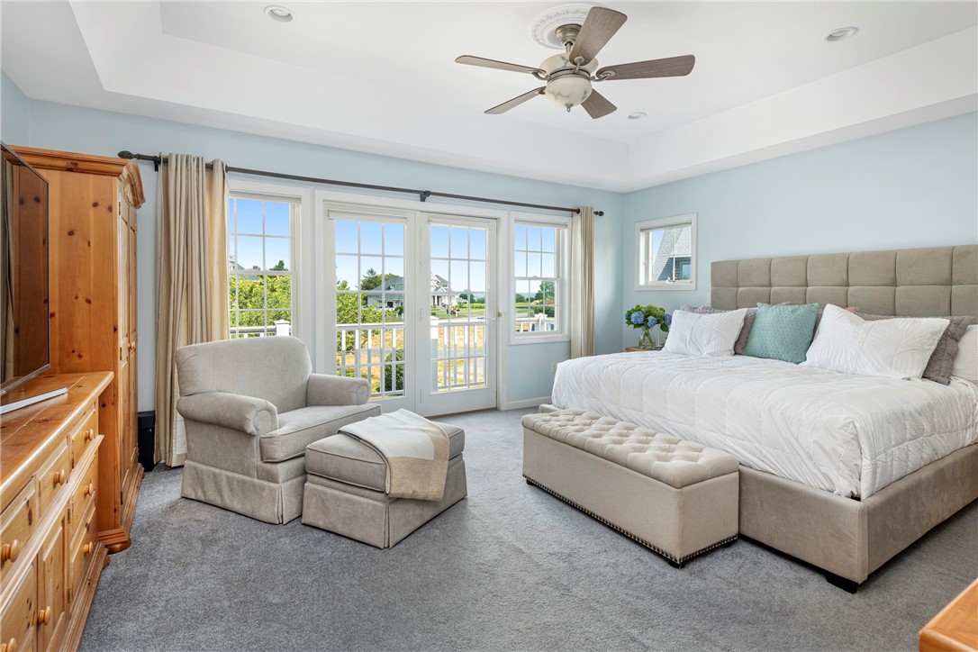 Furnished bedroom with a large upholstered bed, sitting area, and French doors opening to a balcony.
