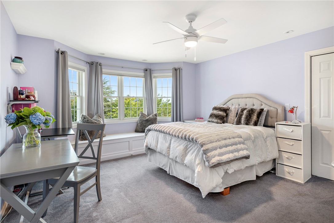 Lavender bedroom with a white bed, three windows, and a built-in window seat.