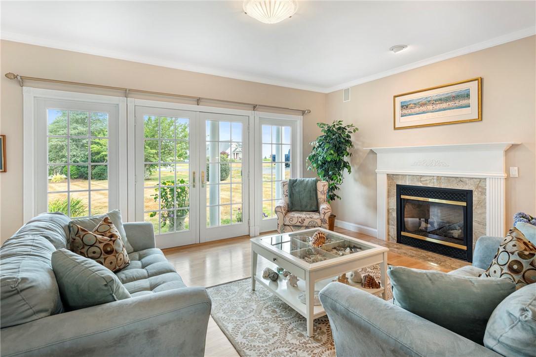 Living room with pale blue sofas, a stone-surround fireplace, and French doors overlooking the yard.