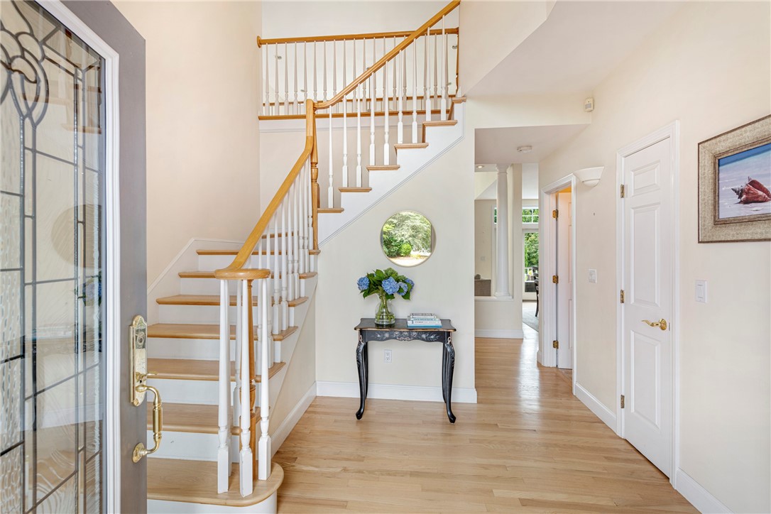 Entry foyer with a curved wood-and-white staircase and console table topped with blue hydrangeas.