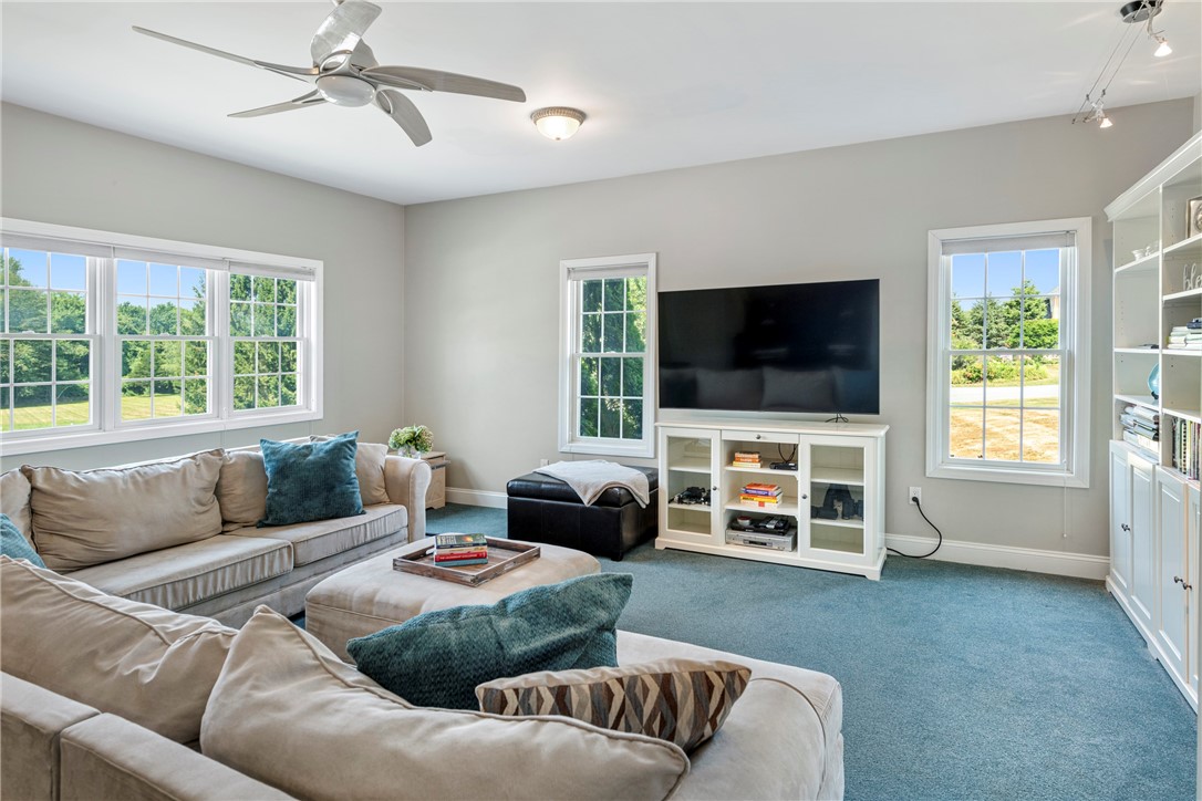 Furnished living room with gray sofas, blue carpet, large windows, and a wall-mounted television.
