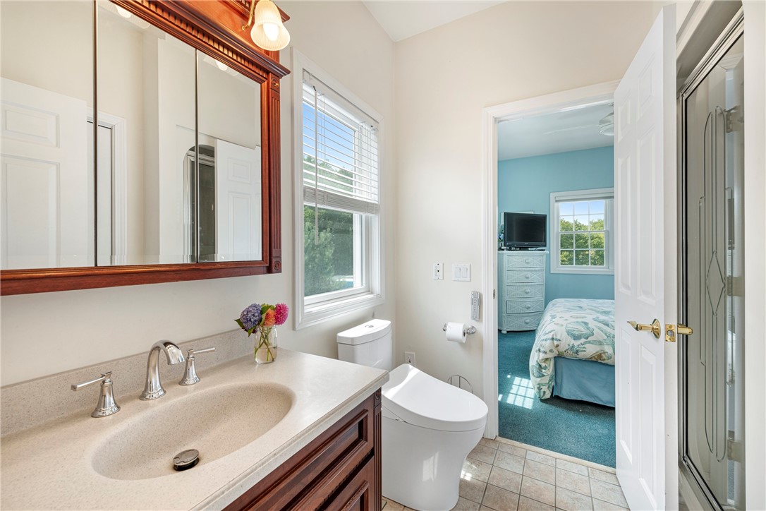 Bathroom with a dark wood vanity and glass shower, looking into a blue bedroom.