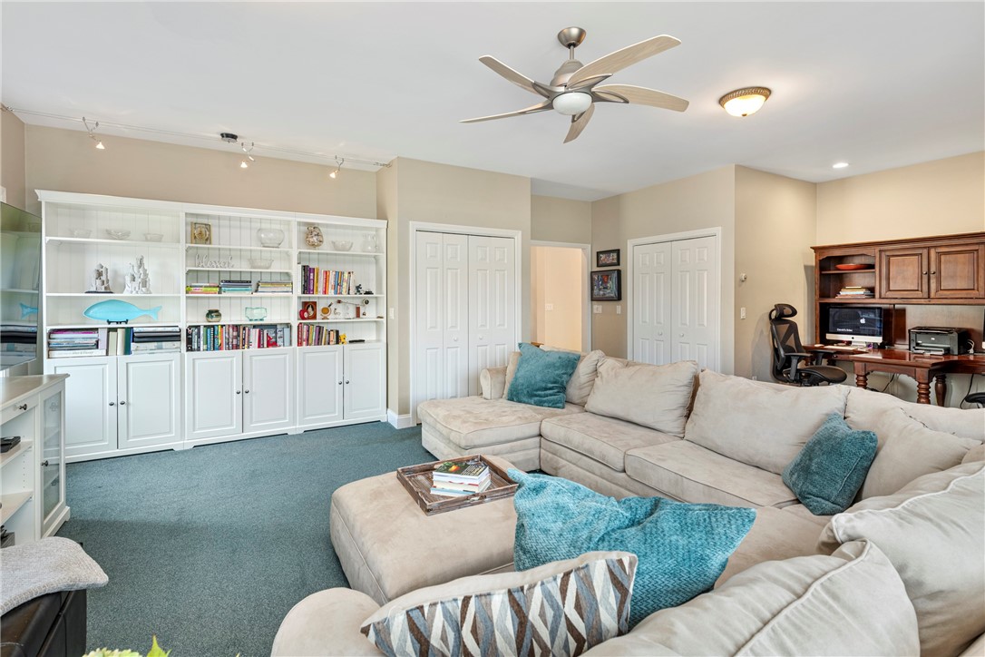 Living room with a beige sectional, white built-in shelving, and teal carpet.