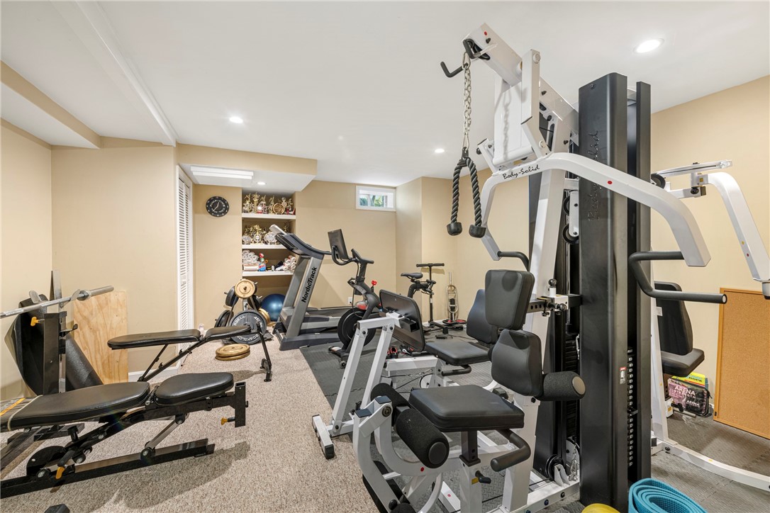 Home gym with weight machines, a treadmill, stationary bikes, and built-in trophy shelves.