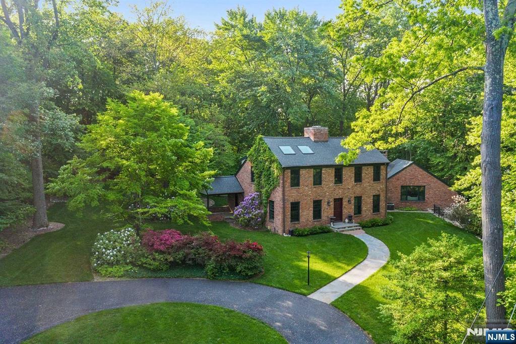 Two-story brick home surrounded by mature trees, with a curved driveway and landscaped grounds.