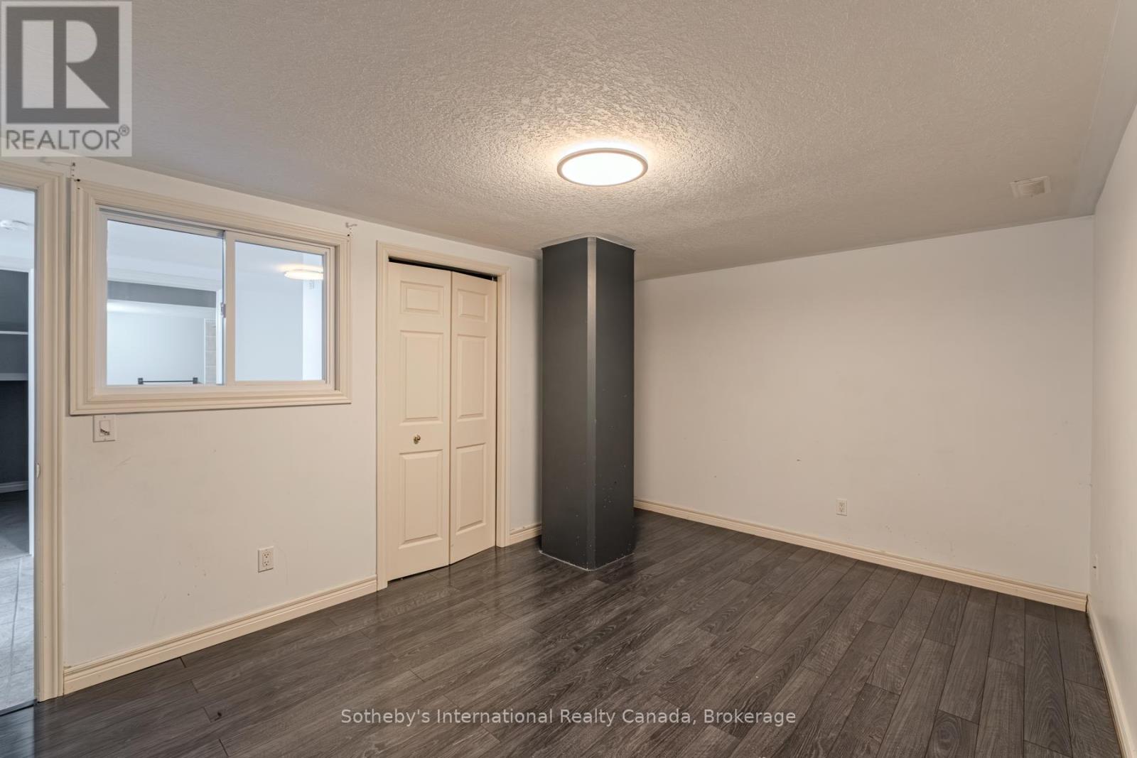 Vacant room with dark plank flooring, a closet, and an interior window.