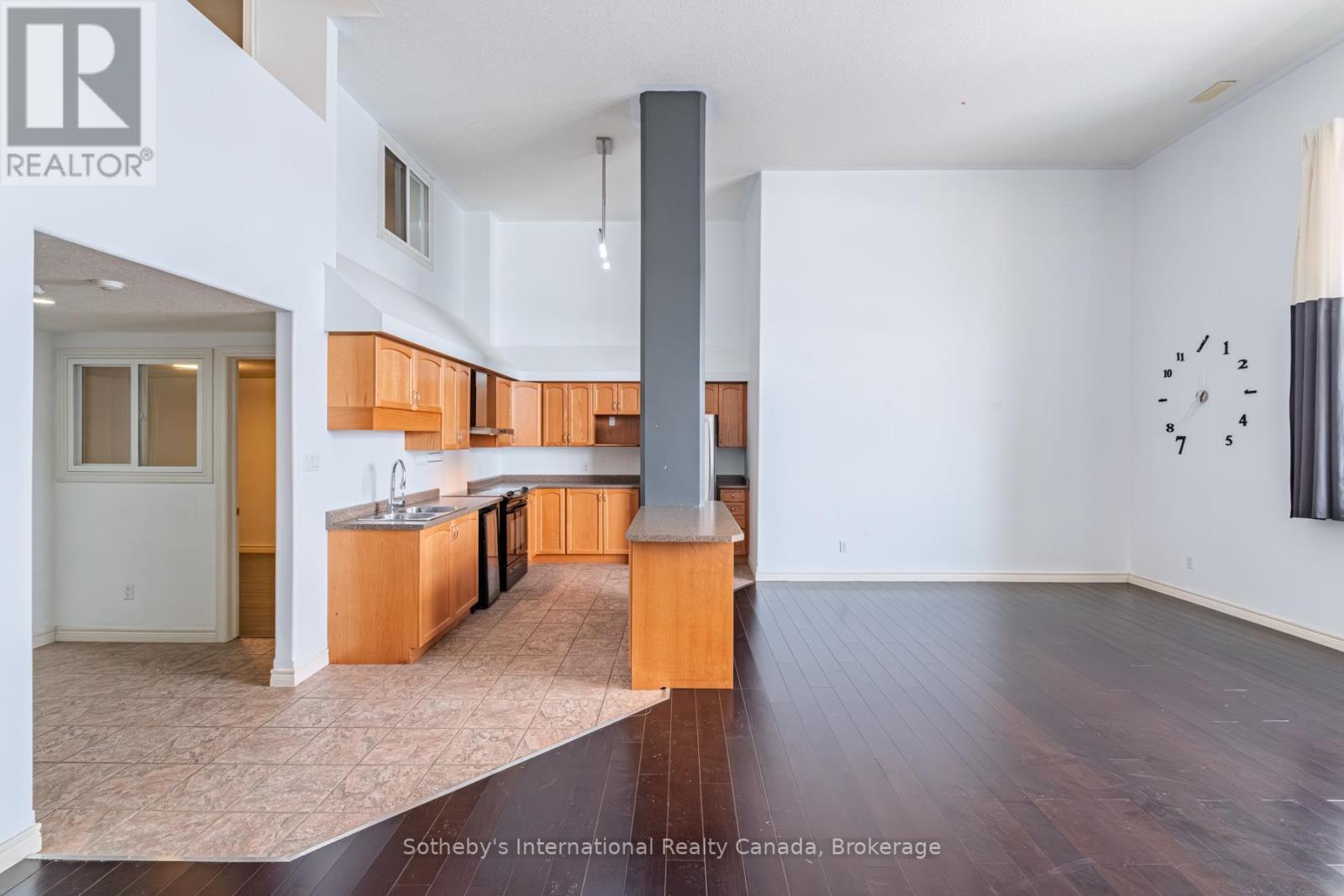 Open-plan kitchen and living area with wood cabinetry, a peninsula, and dark flooring.