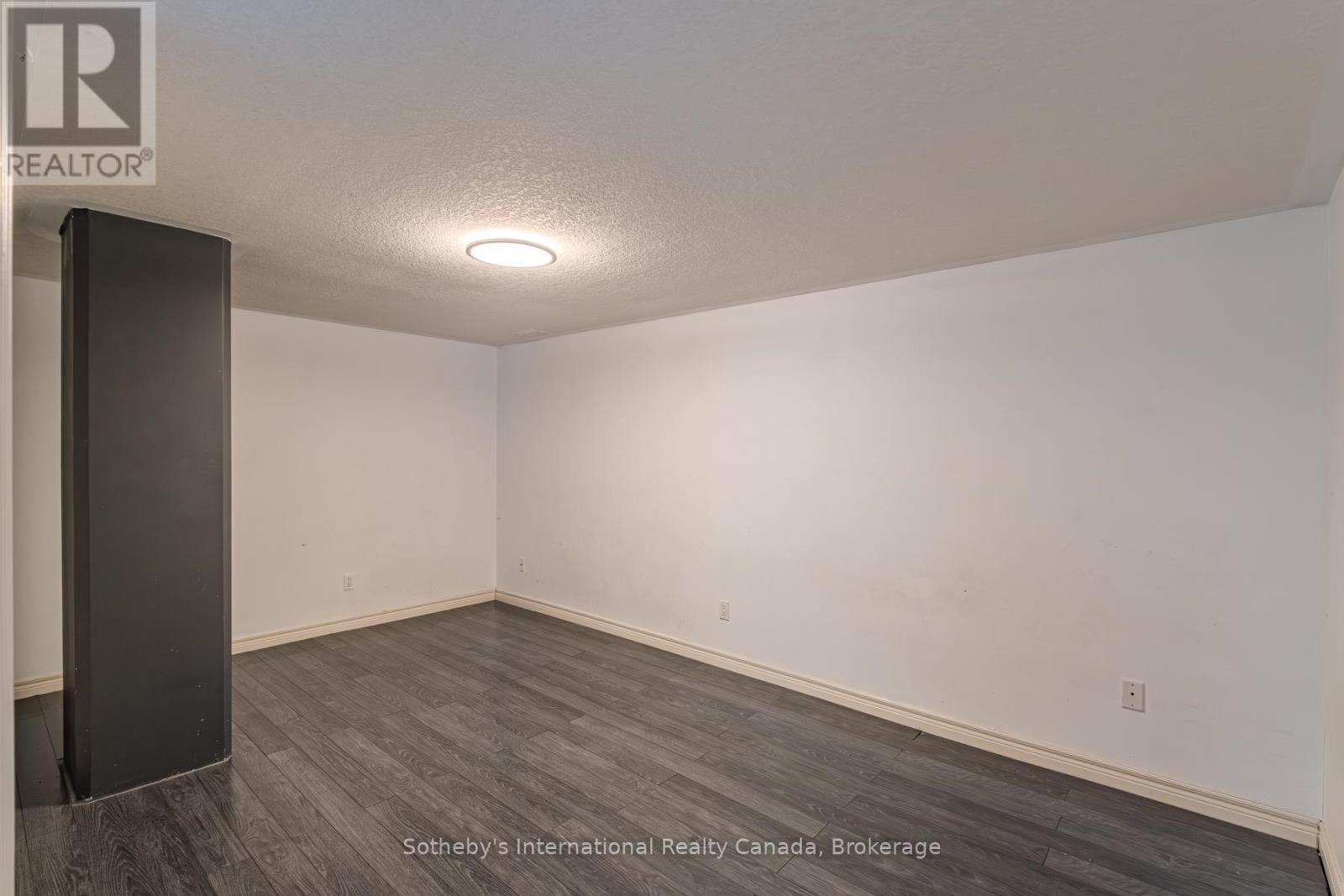 Empty room with gray plank flooring, white walls, and a dark partition.