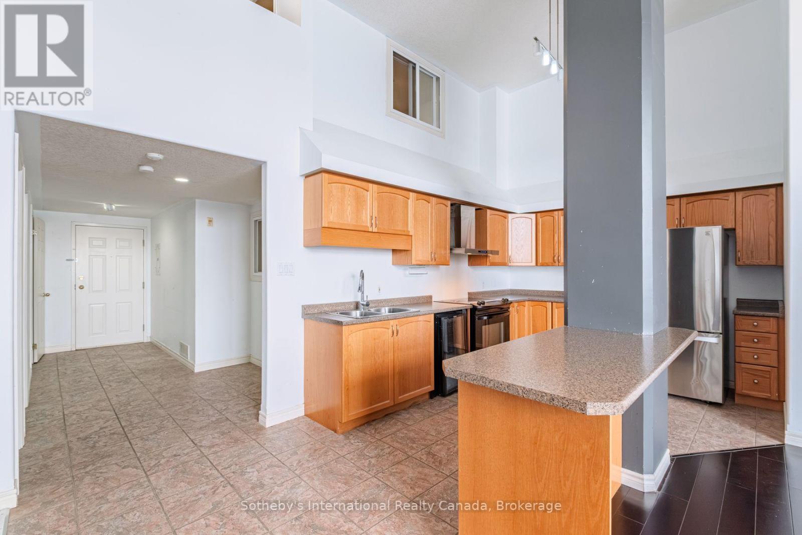 Kitchen with honey-colored cabinets, a large peninsula, and a tiled floor.