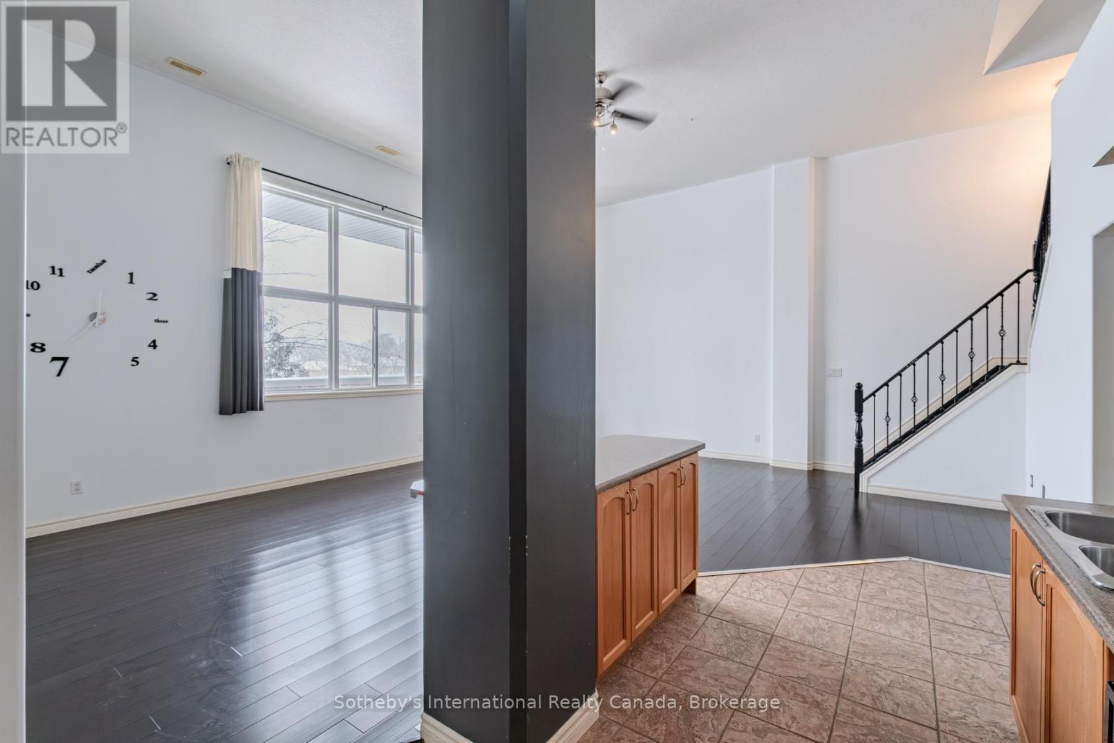 Open kitchen and living area with dark floors, wood cabinetry, and a staircase.